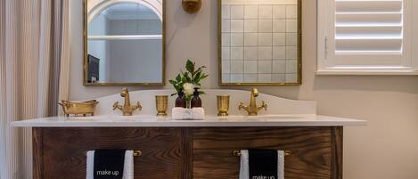 A bathroom with a double sink, two mirrors, and a wicker basket.