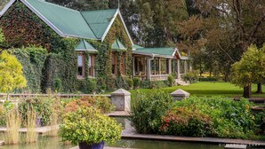 A building with a green roof, surrounded by lush gardens and a pond. - Hartford House (Mooirivier)