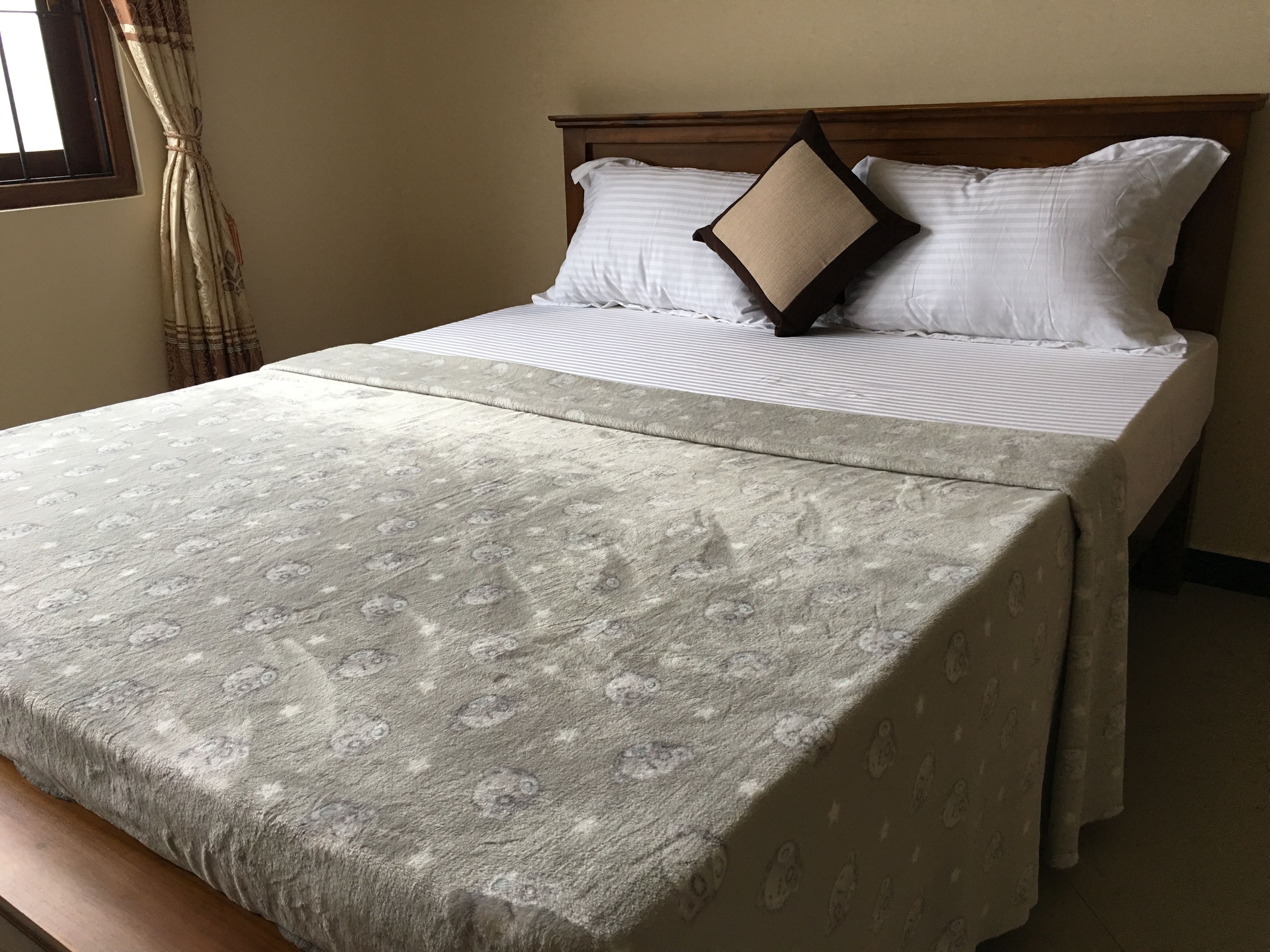 Una cama con colcha estampada, dos almohadas y cabecera de madera.