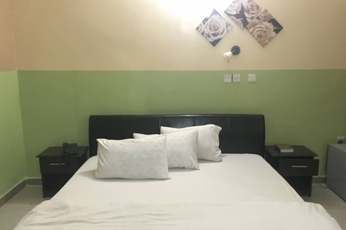 A bedroom with a bed, two nightstands, a lamp, and floral wall art.