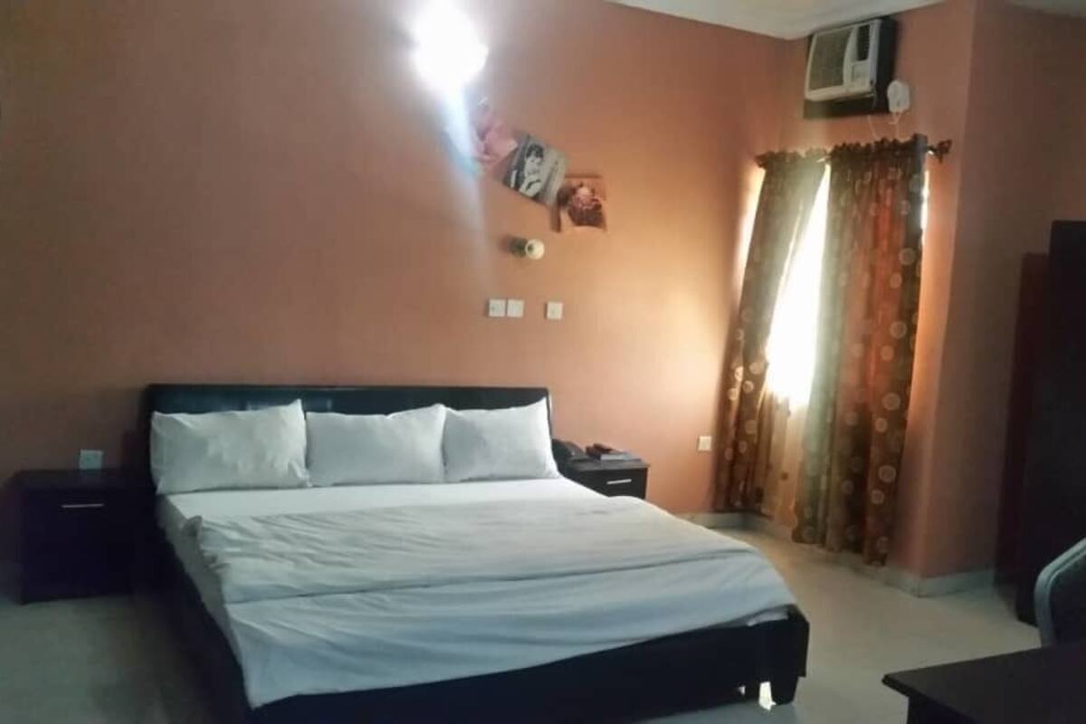 A bedroom with a bed, a nightstand, a wardrobe, and a curtain.
