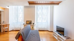 Un salon avec un canapé, un téléviseur et une petite table sur laquelle se trouve une lampe.