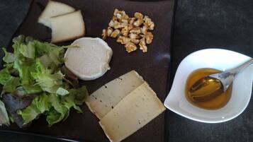 A plate with cheese, walnuts, and a bowl of honey.