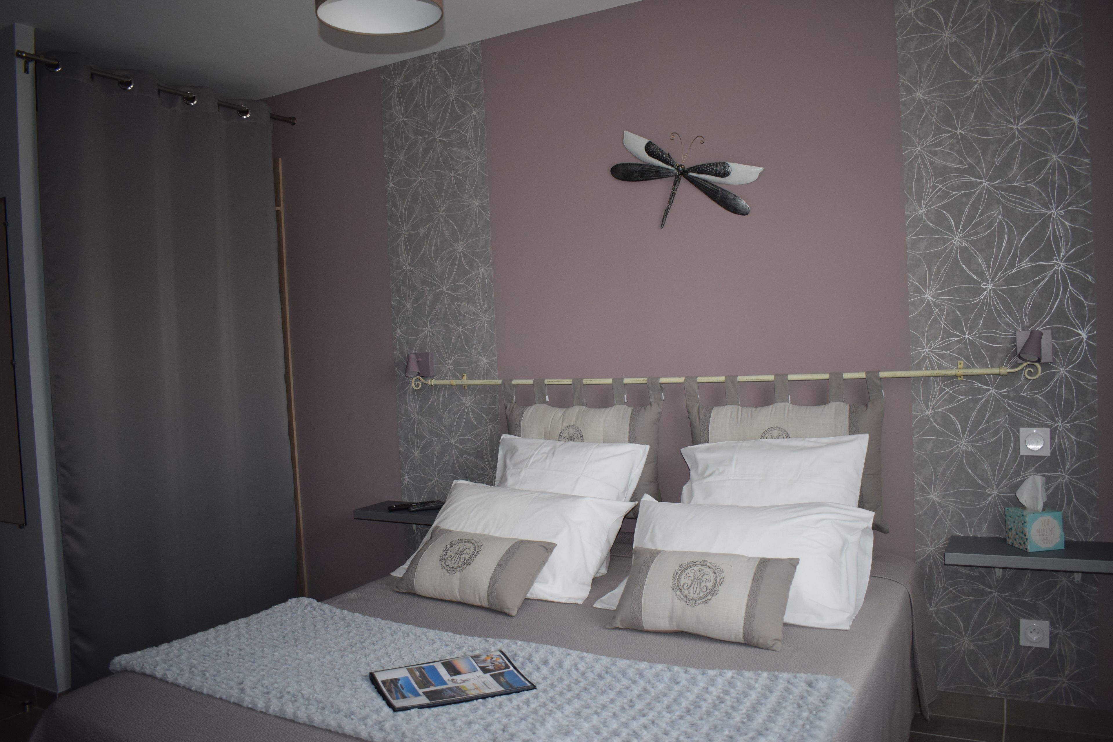 Una cama bien hecha con muchas almohadas y un adorno en la pared.