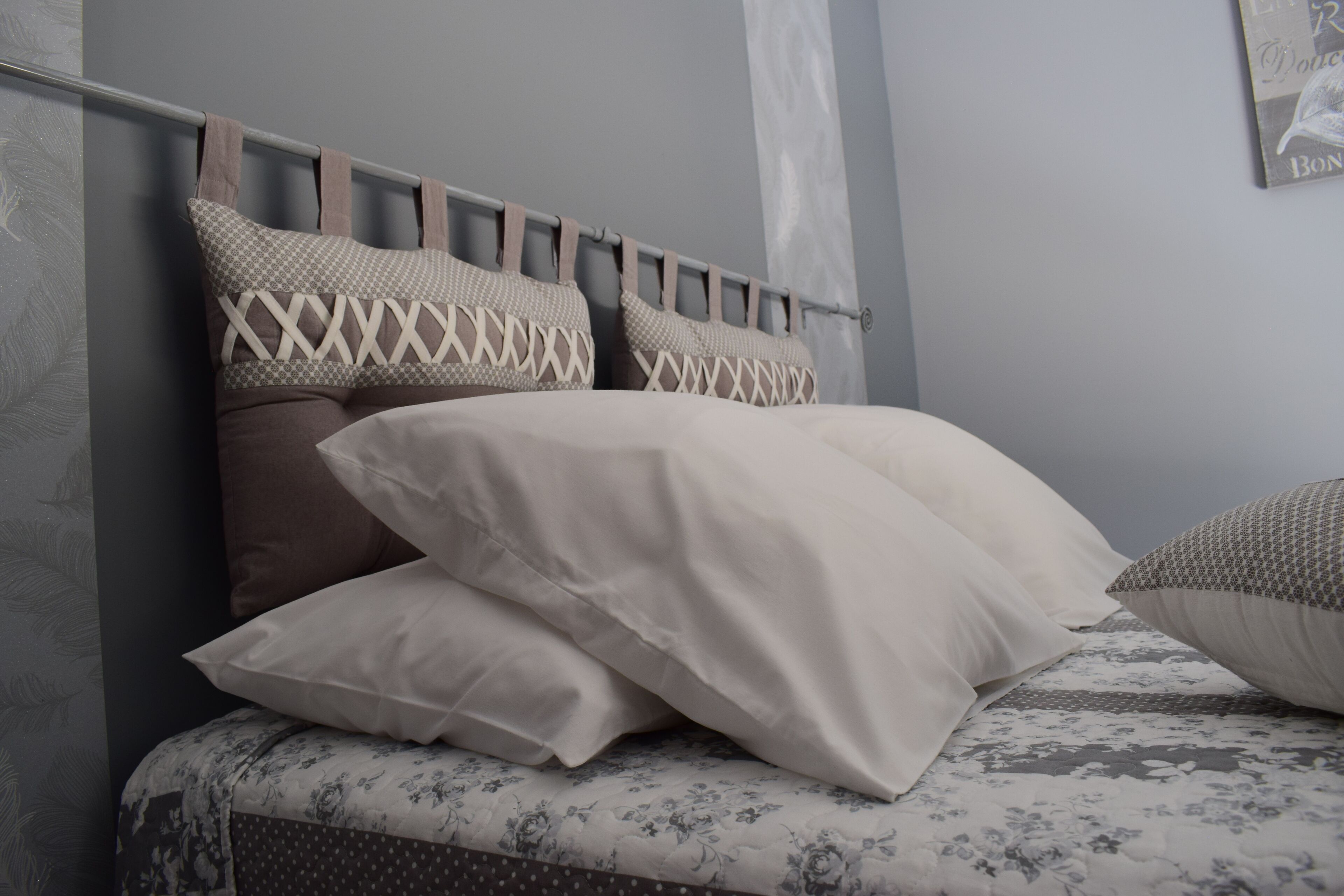 A neatly made bed with patterned pillows and a floral bedspread.
