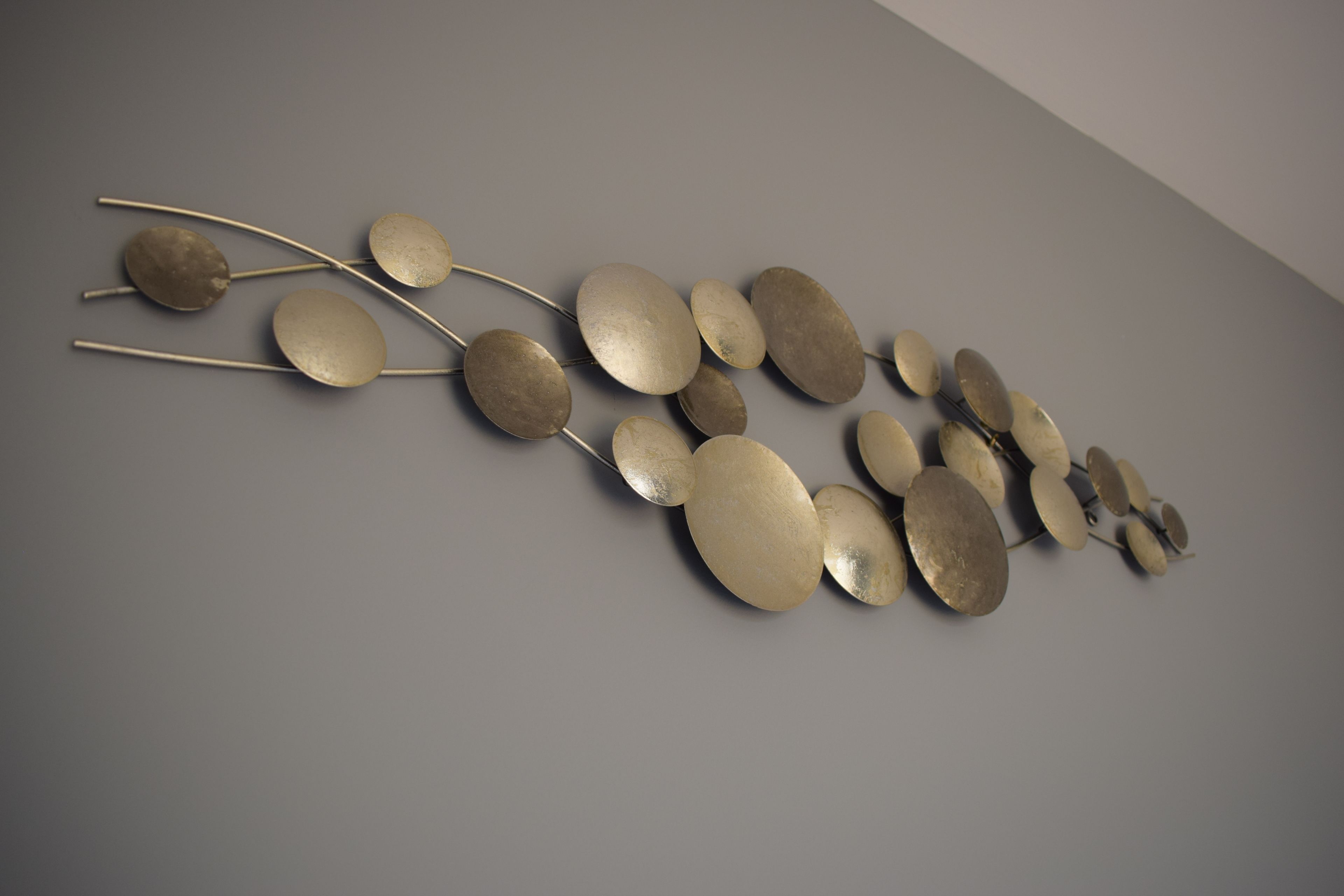 A wall-mounted abstract art installation with metallic elements.