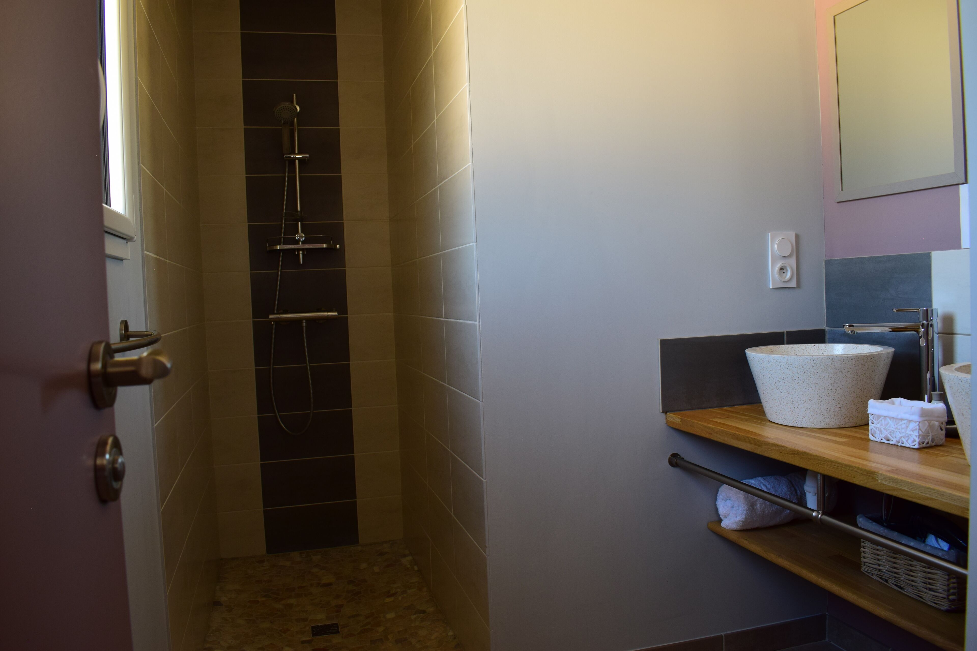 Een badkamer met een douche, wastafel en spiegel.