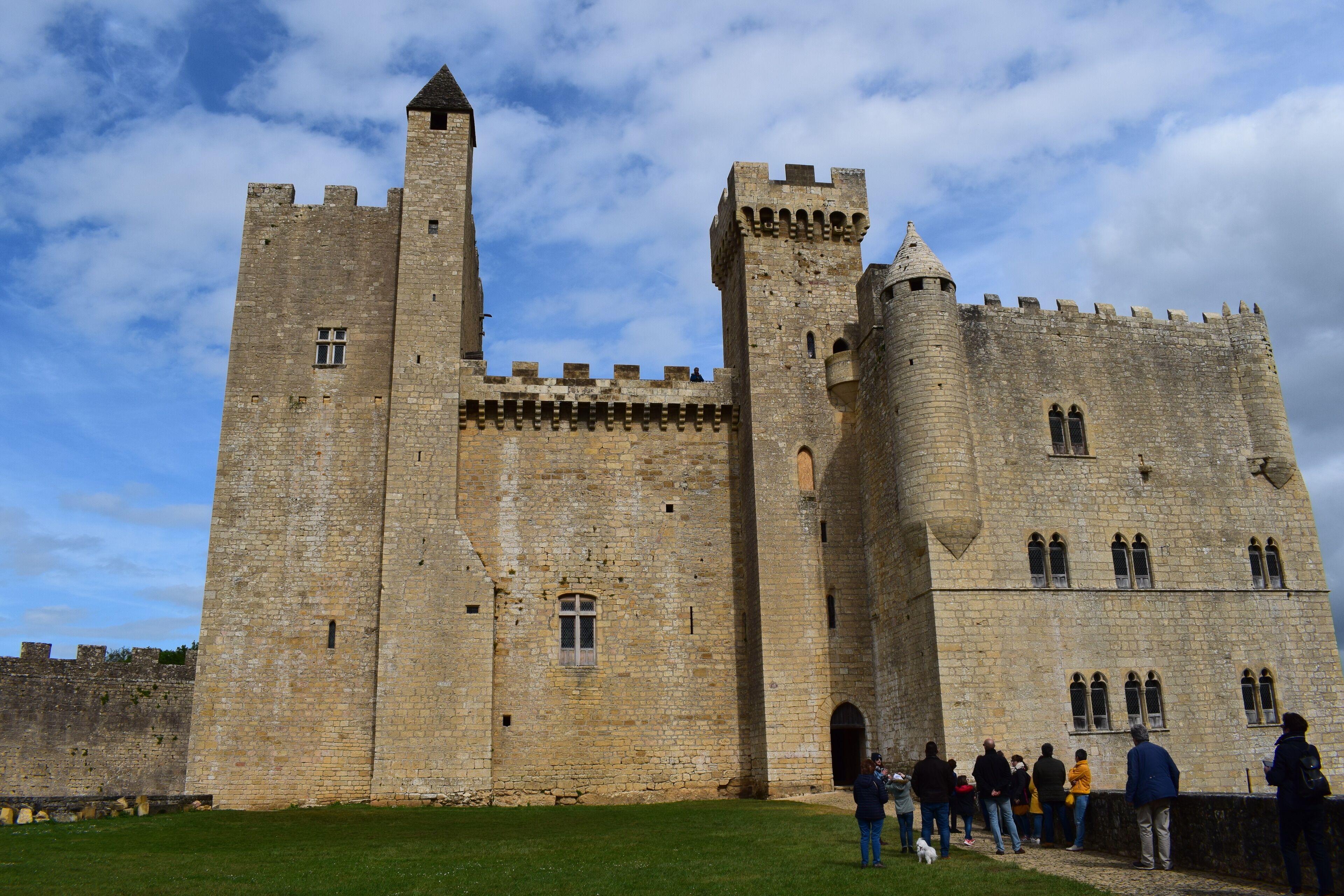 A historic stone castle with multiple towers and battlements, surrounded by a grassy area.