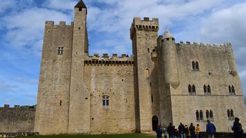 A historic stone castle with multiple towers and battlements, surrounded by a grassy area.