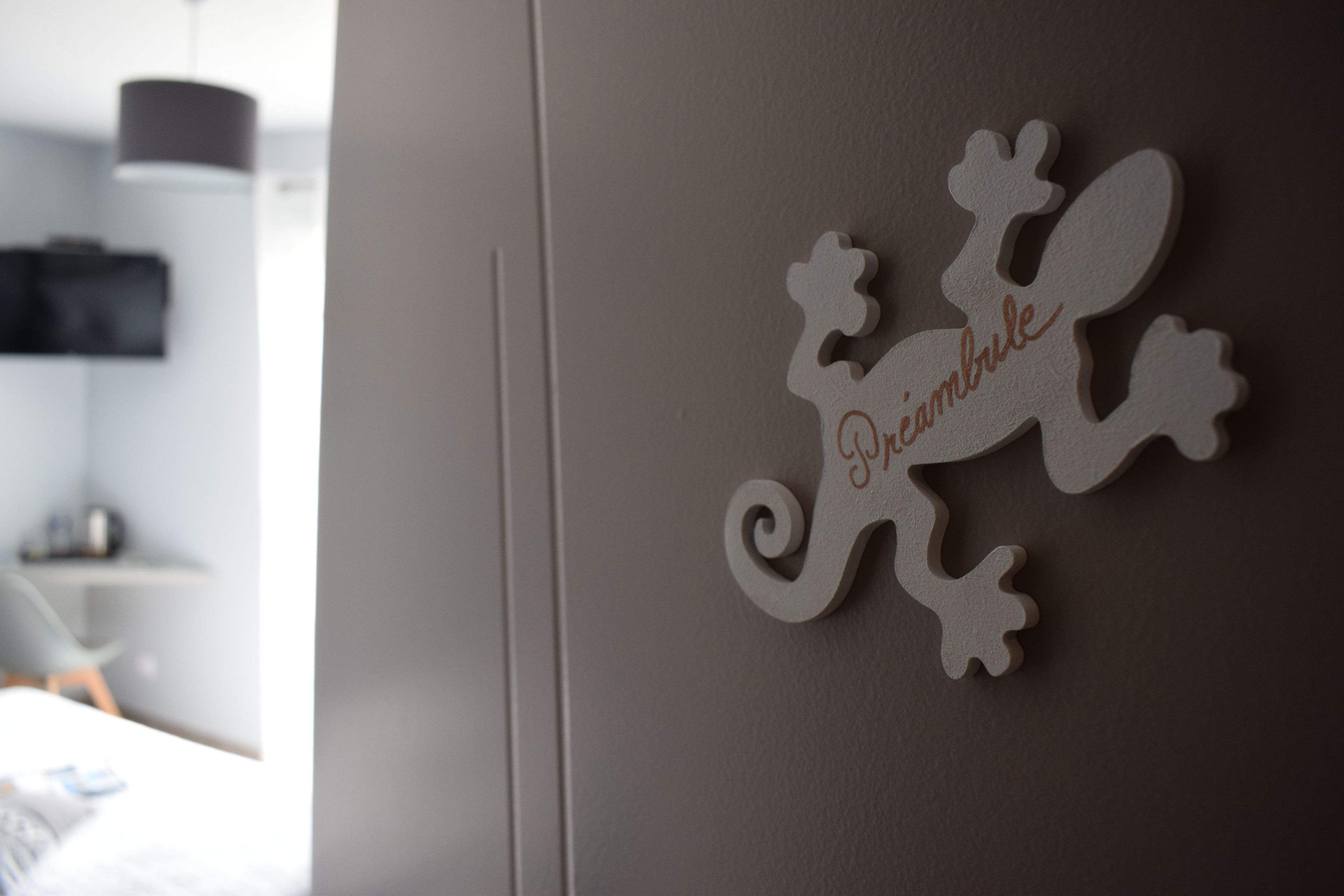 Een muur met een decoratief object, waarop een gestileerd dier en de tekst 'Oniambule' staan.