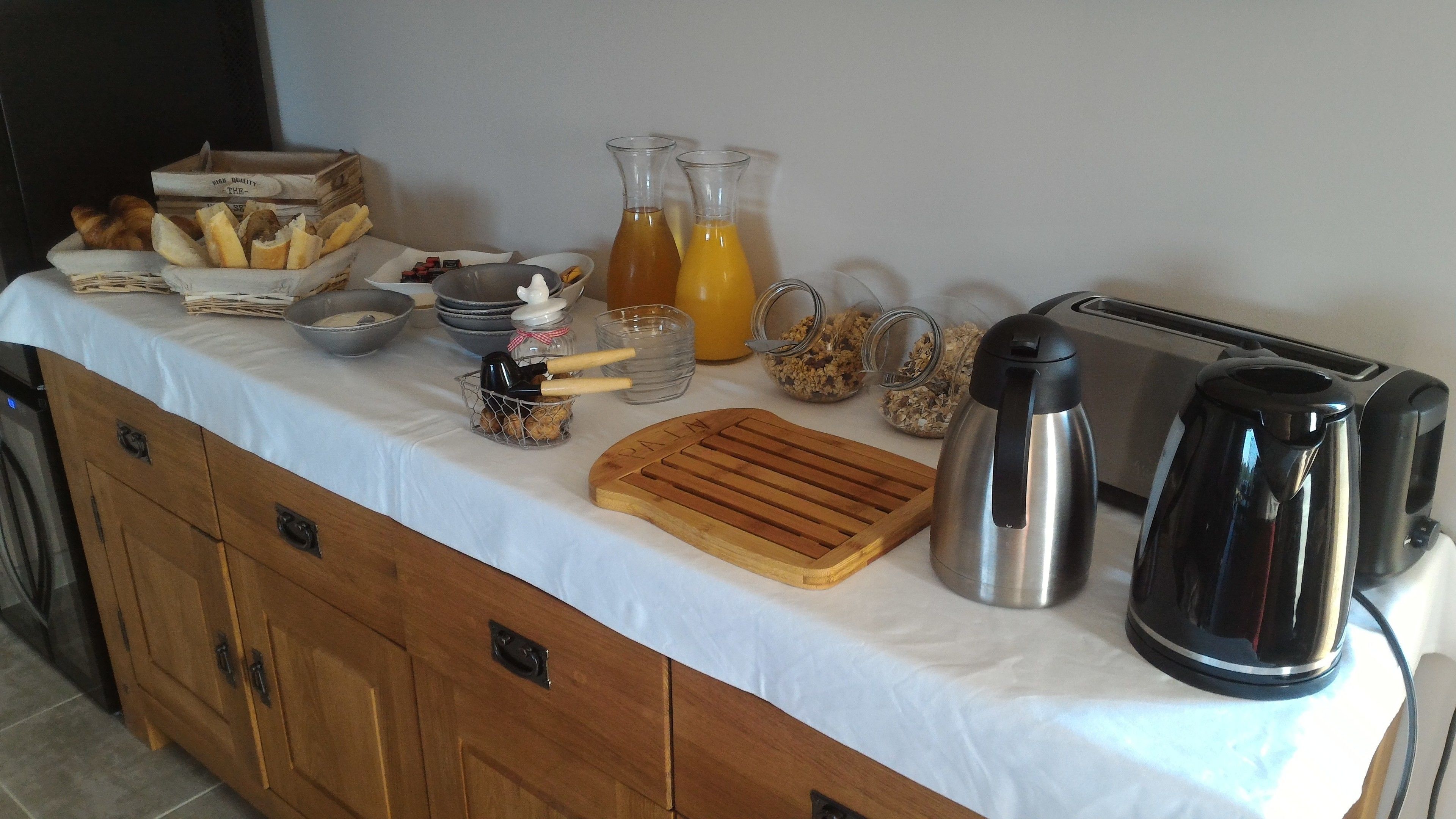 Ein reichhaltiges Frühstücksbuffet mit Brot, Gebäck, einer Kaffeemaschine, einem Toaster und einer Obstschale.