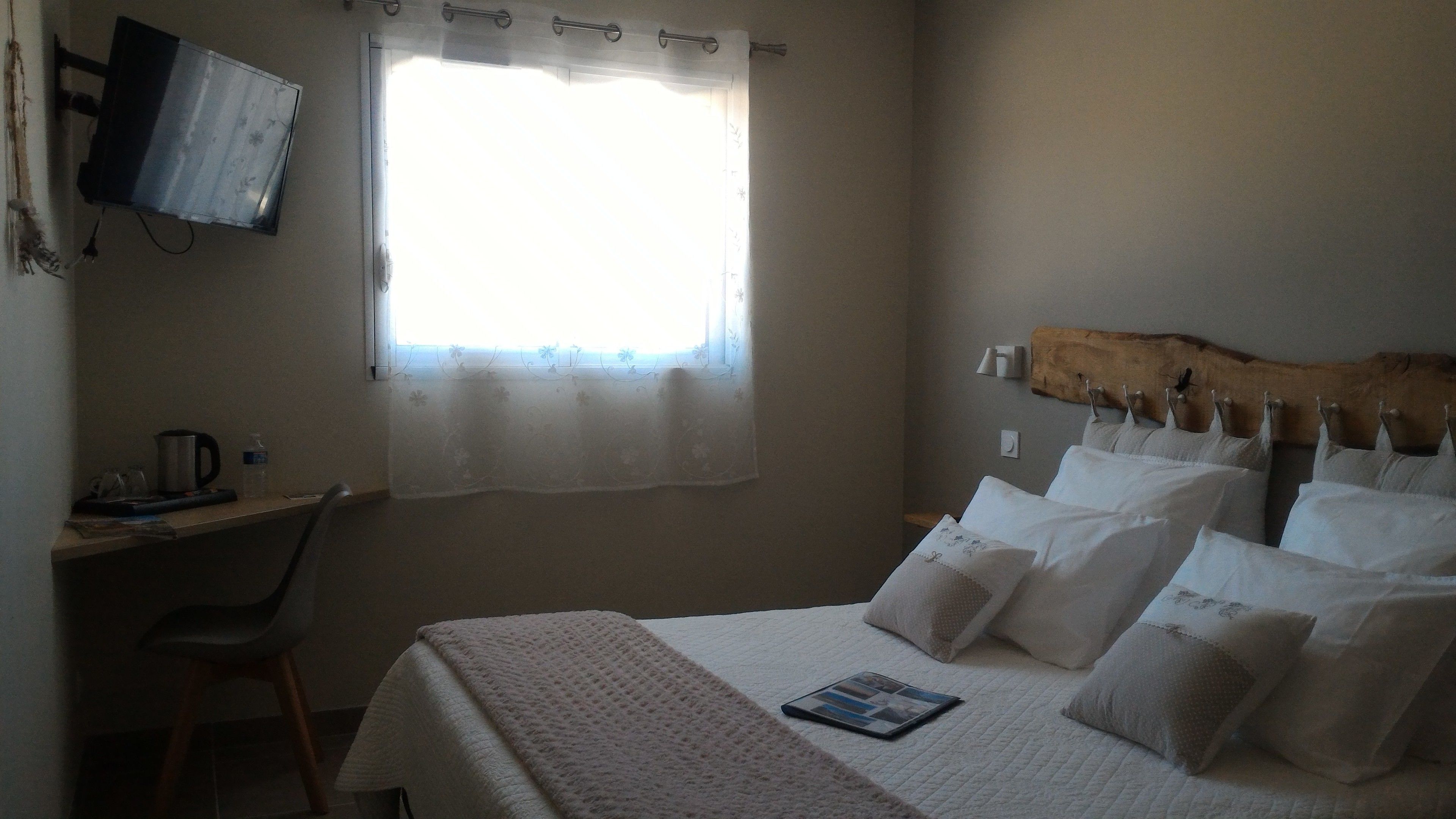 Ein Schlafzimmer mit einem Bett, einem Schreibtisch und einem an der Wand befestigten Fernseher.