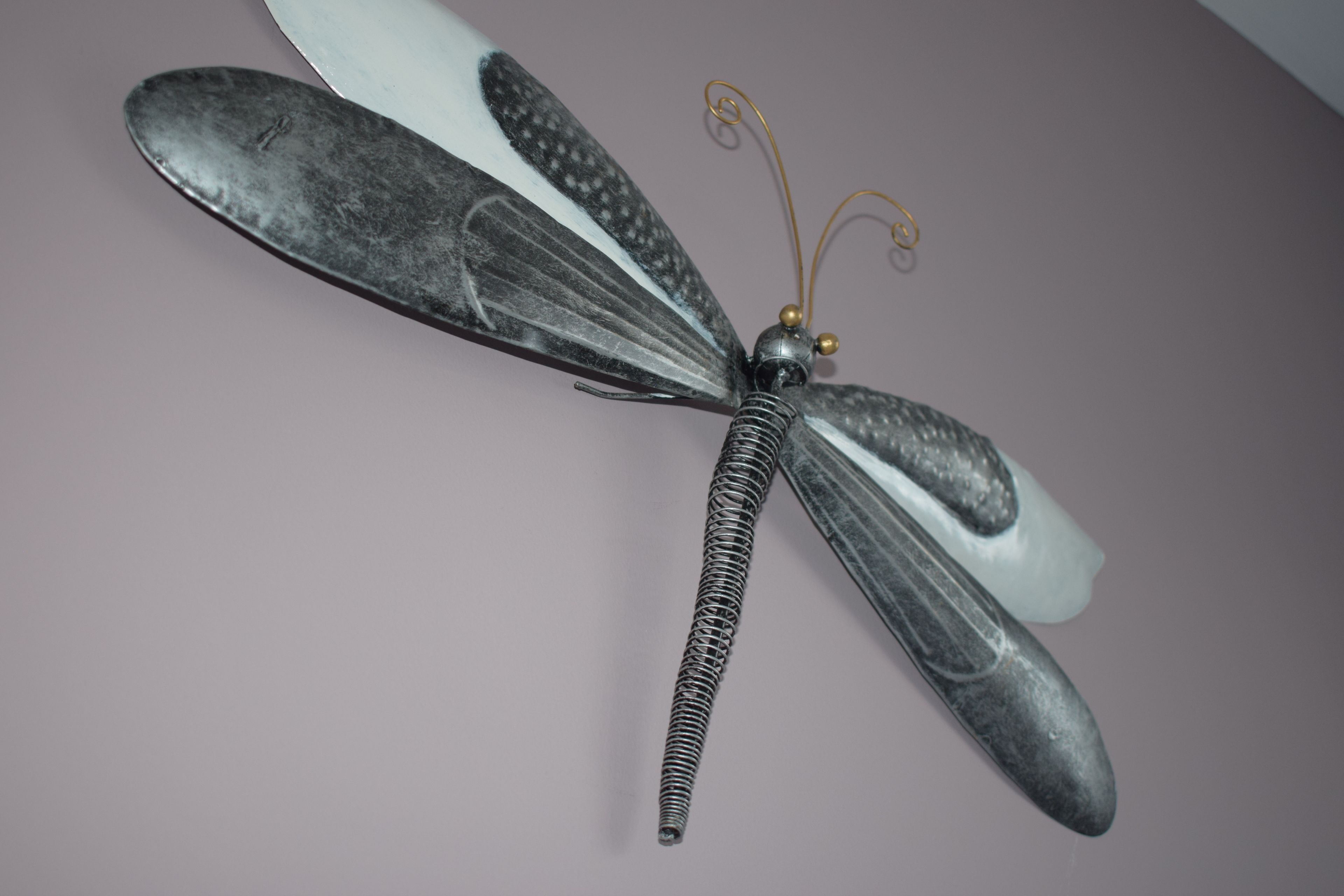 Une libellule décorative aux ailes métalliques et au corps segmenté.