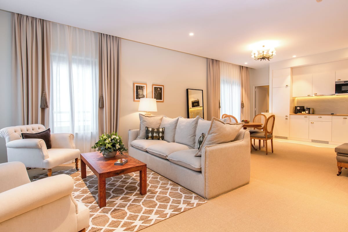 A modern living room with a sofa, armchairs, a coffee table, and a dining area with a table and chairs.