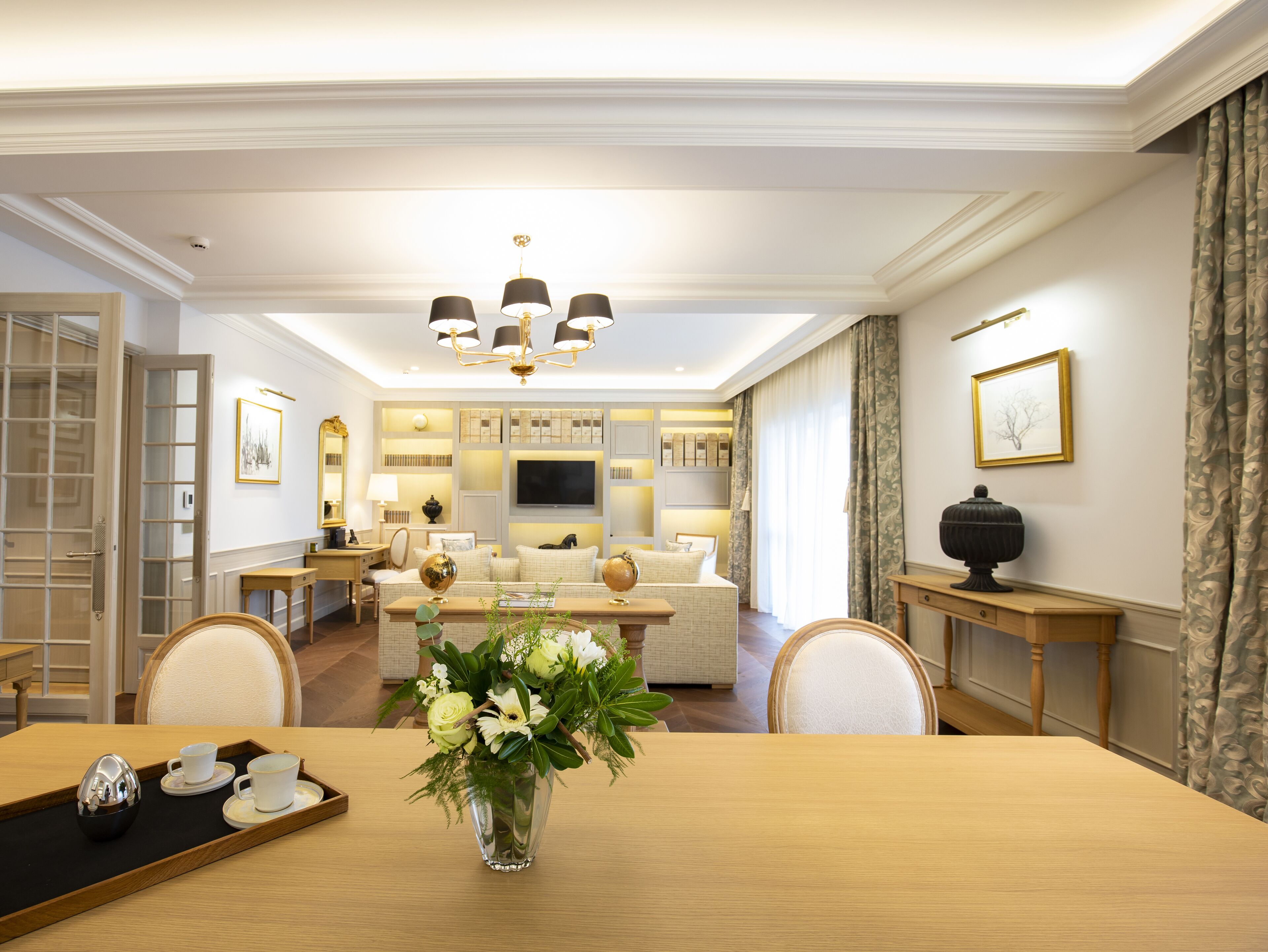 A spacious dining area with a wooden table, chairs, and a vase of flowers.