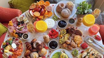 Una mesa redonda con diversas comidas y bebidas, rodeada de cojines estampados.