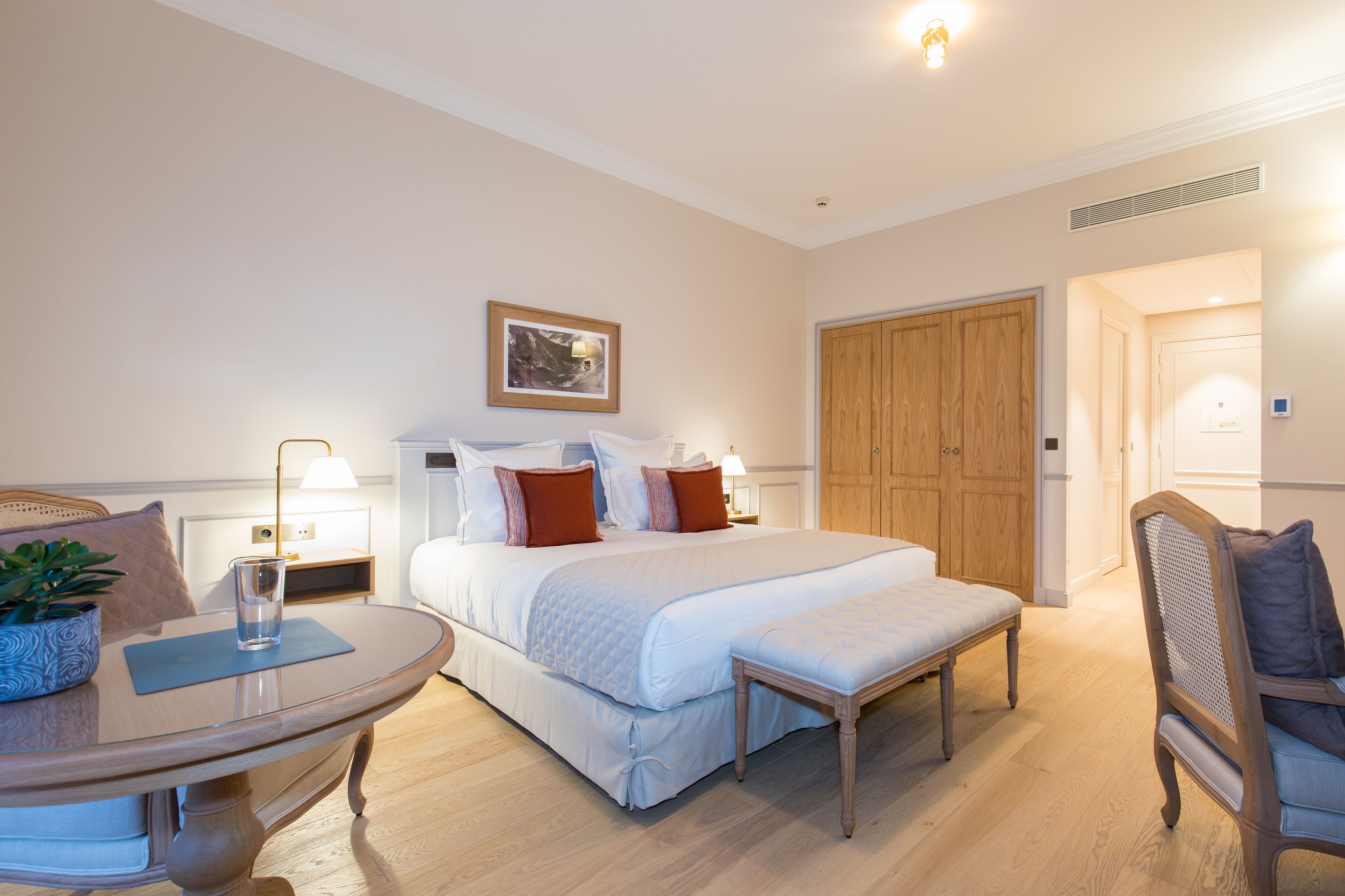 A hotel room with a bed, bedside table, lamp, and a wooden wardrobe.