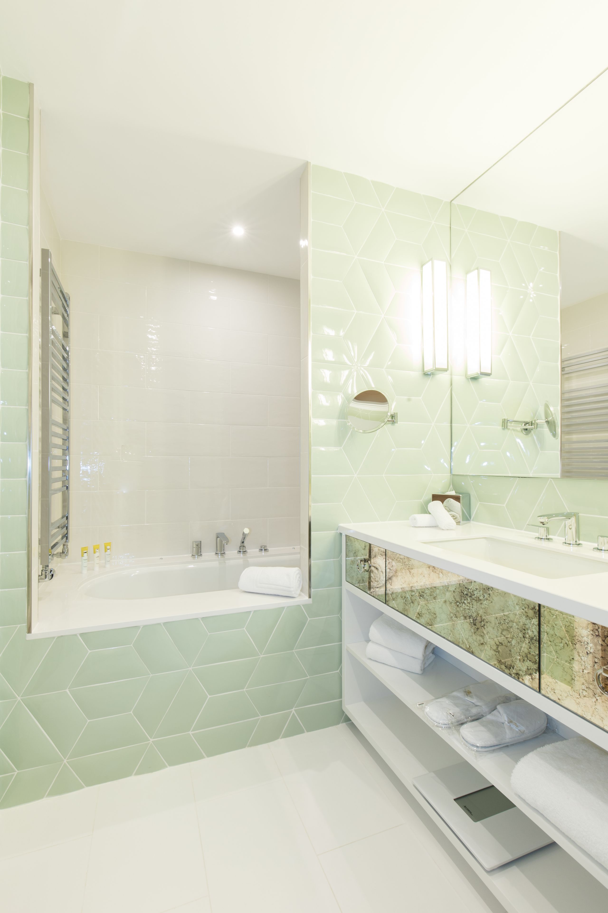 A modern bathroom with a freestanding bathtub, a vanity with a mirror, and a built-in shelf with towels.