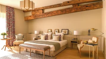 Un dormitorio con una cama grande, una viga de techo de madera, una mesita de noche con lámpara, una silla y una pequeña mesa con lámpara.