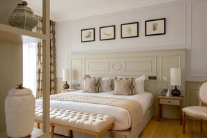 A bedroom with a large bed, a bedside table, a chair, and a mirror.