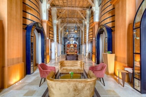 Un hall espacioso con techo alto, vigas de madera y una zona de estar central con sillones cómodos y una mesa de centro.