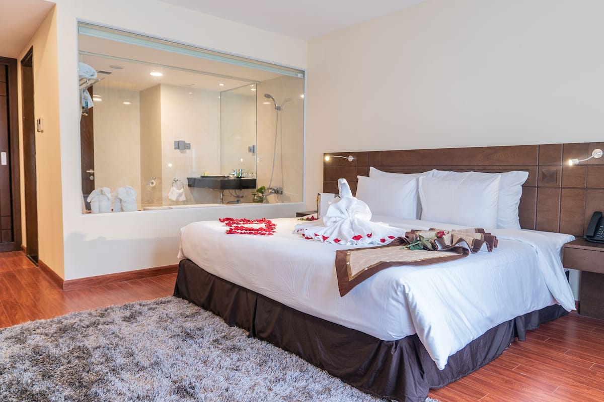 Une chambre d’hôtel avec un grand lit, une tête de lit en bois, un miroir et un plancher en bois.