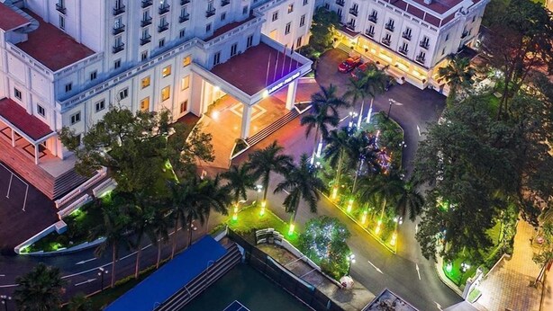 Ett hotell med flera våningar, ett iögonfallande skylt, en pool på taket och ett väl upplyst parkeringsområde.