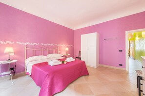 Un dormitorio con decoración rosa, una cama, mesitas de noche y un armario.