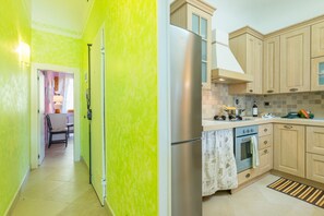 Una cocina con refrigerador de acero inoxidable, armarios de madera, salpicadero de azulejos y una ventana con vista al espacio.