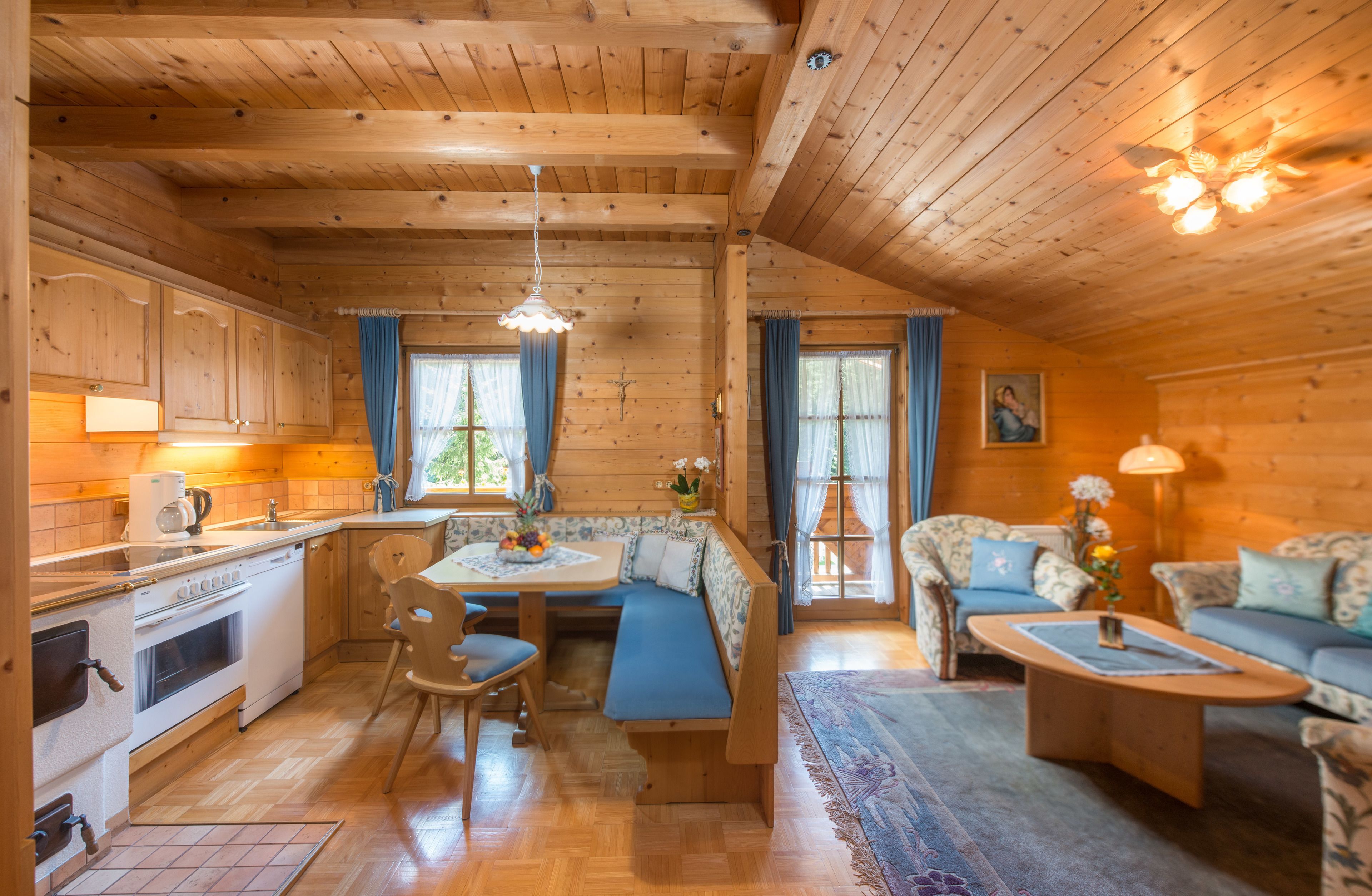 Ein gemütliches Blockhaus-Interieur mit Holzwänden, einem Essbereich mit einer Bank, einer Couch und einem Couchtisch.