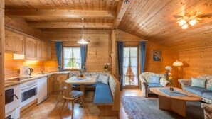 A cozy cabin interior with wooden walls, a dining area with a bench, a sofa, and a coffee table. - Meine Heimat (Ramsau am Dachstein)
