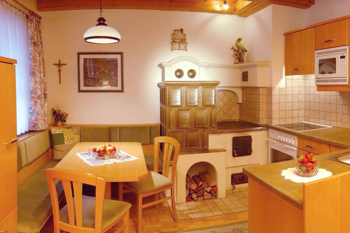 Uma cozinha acolhedora com armários de madeira, uma mesa de jantar com cadeiras, forno embutido e lareira.