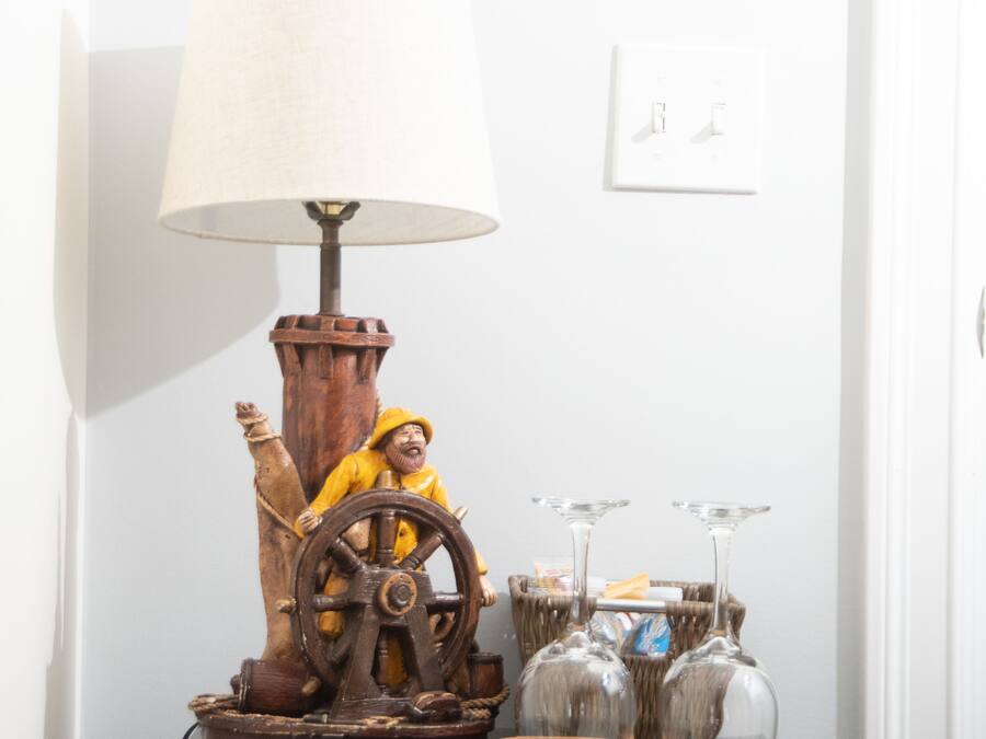 Et træbord med en lampe, et indrammet billede og vinglas.