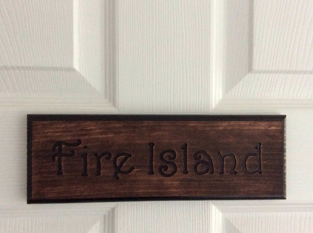 A wooden nameplate with the text "Fire Island" mounted on a white door.