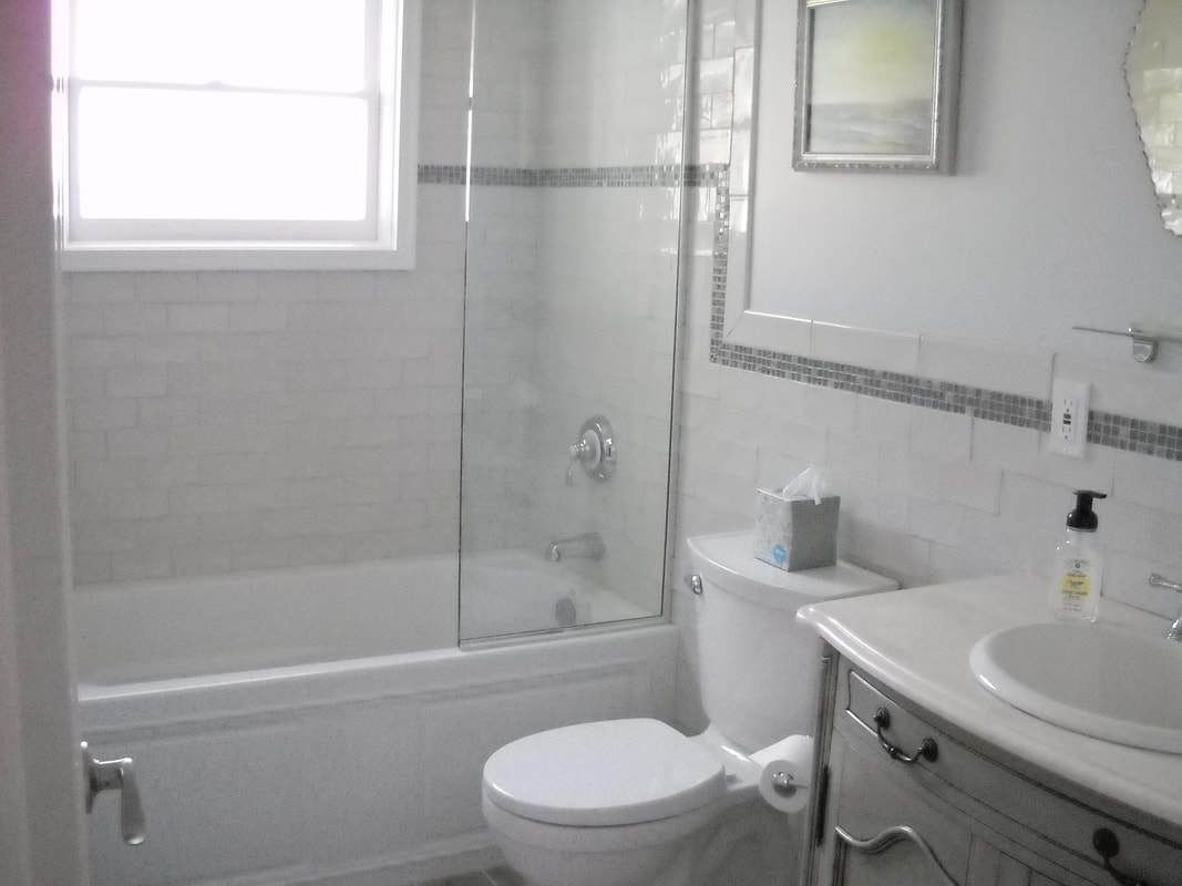 A bathroom with a glass-enclosed shower, a toilet, and a sink with a mirror above it.