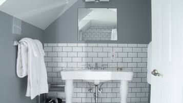 A bathroom with a white sink, a towel rack with a towel, a mirror, and a tiled wall.