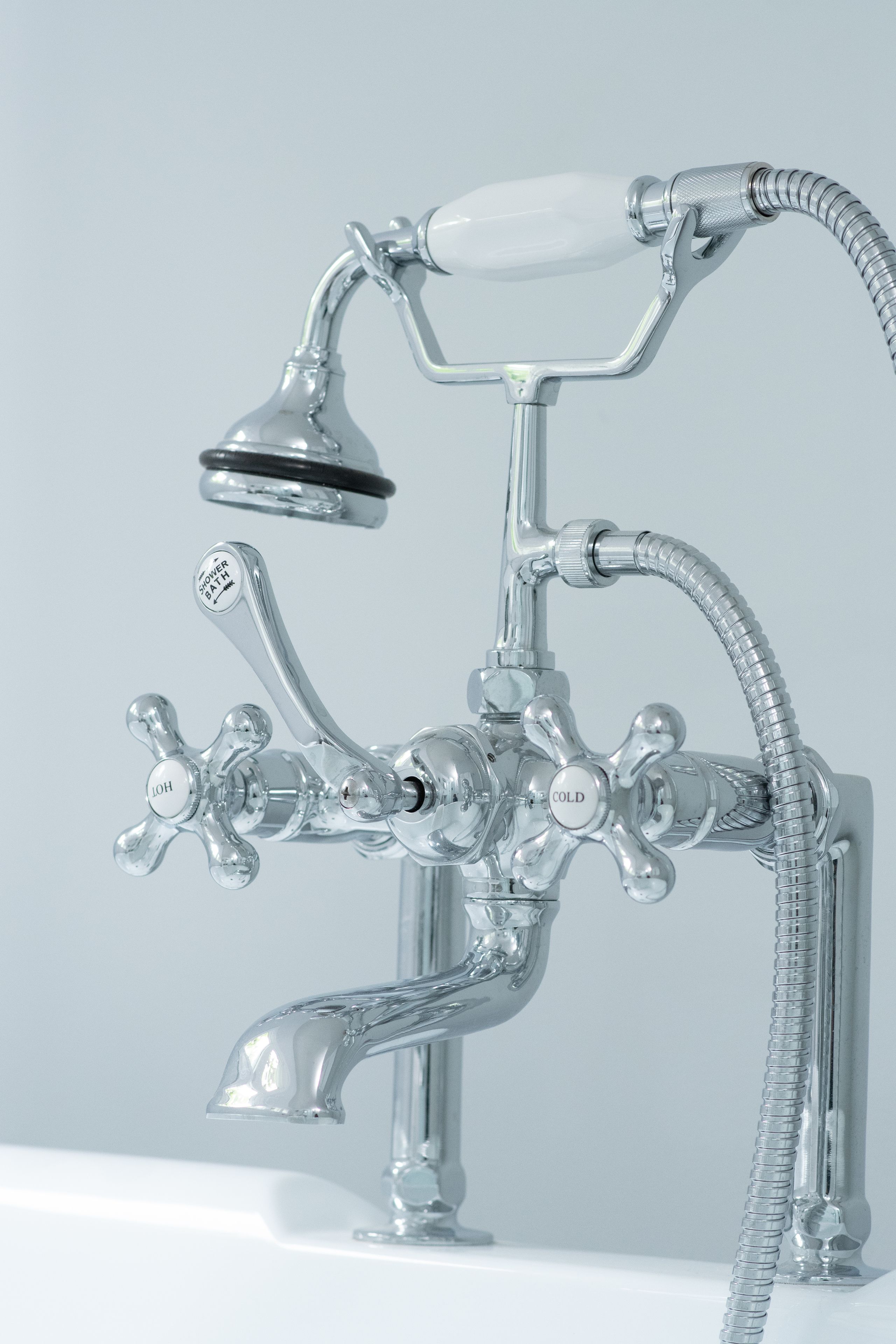 Un accesorio de baño cromado con múltiples controles, incluyendo un cabezal de ducha de mano y una manguera flexible.