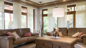 A spacious living room with a brown leather sofa, a wooden coffee table, and large windows allowing natural light. - Hotel & Restaurant Becher (Donzdorf)