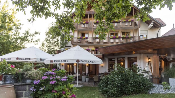 A hotel with outdoor seating, potted plants, and a statue. - Hotel & Restaurant Becher (Donzdorf)