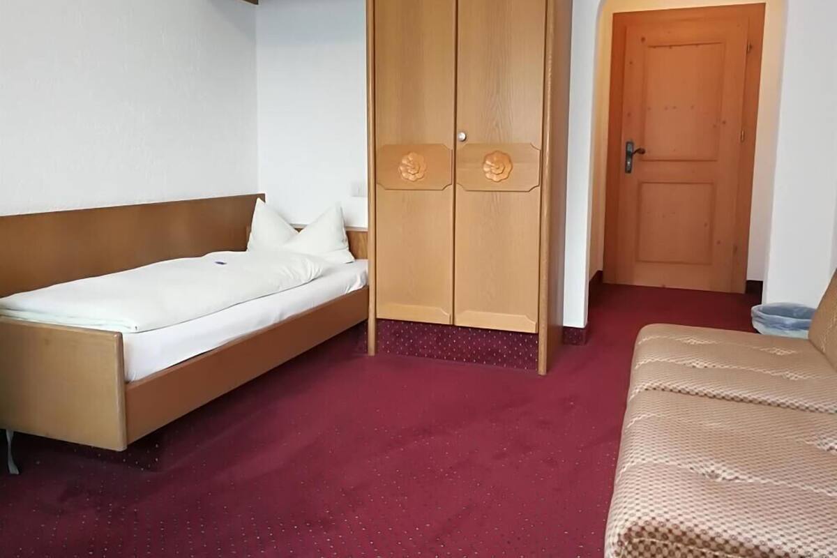 A room with a bed, a wardrobe, and a sofa.