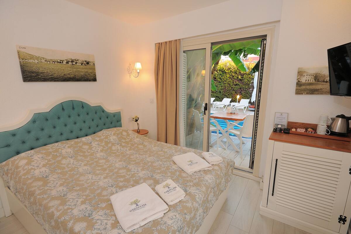 Une chambre d’hôtel avec un lit, une télévision, un balcon donnant sur une piscine et une vue sur la ville.