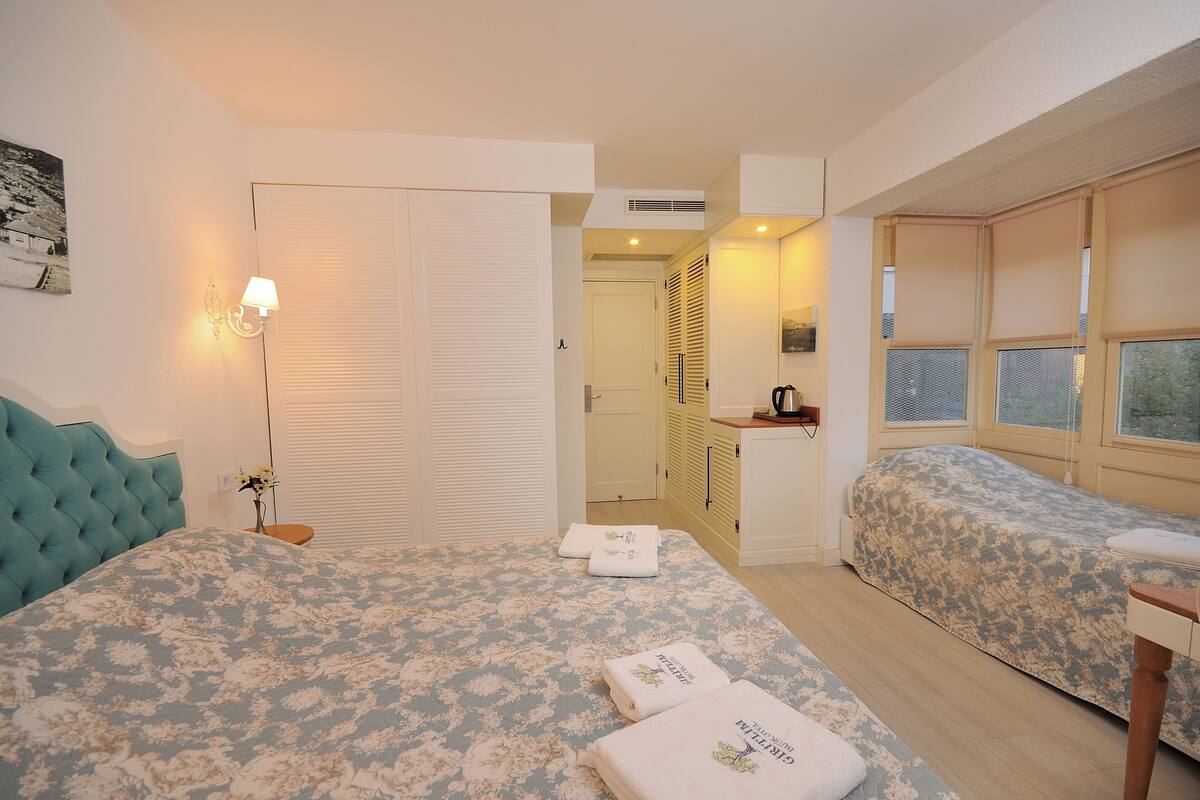Une chambre à coucher avec un grand lit, deux tables de chevet, une armoire et une fenêtre avec des stores.