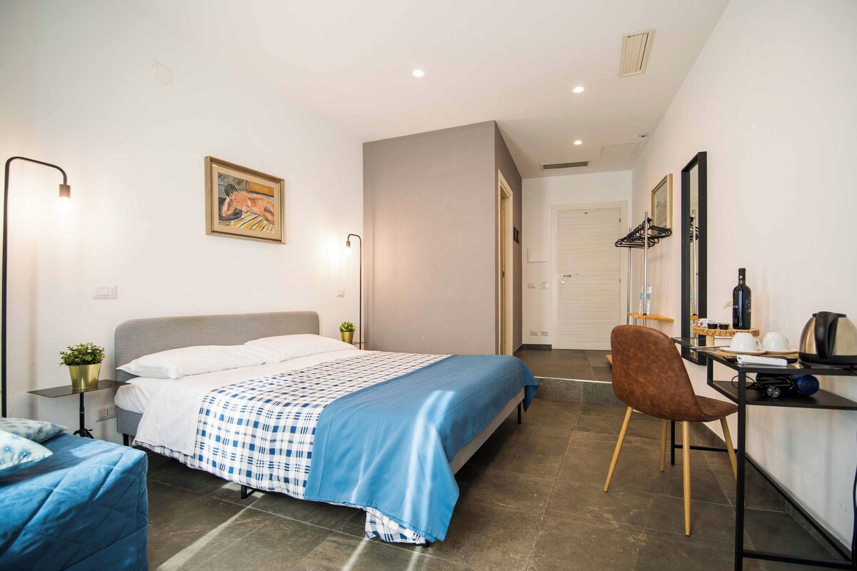 A bedroom with a bed, bedside table, lamp, and a chair.