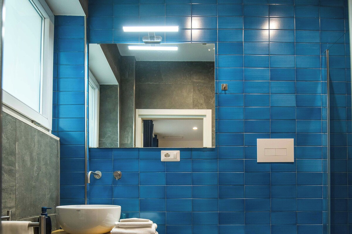 A bathroom with blue tiles, a white sink, a bidet, and a toilet.
