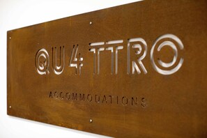 A sign with the text "QU4 TTRC" and "ACCOMMODATIONS" on a brown metal surface. - Quattro Briganti (Salerno)
