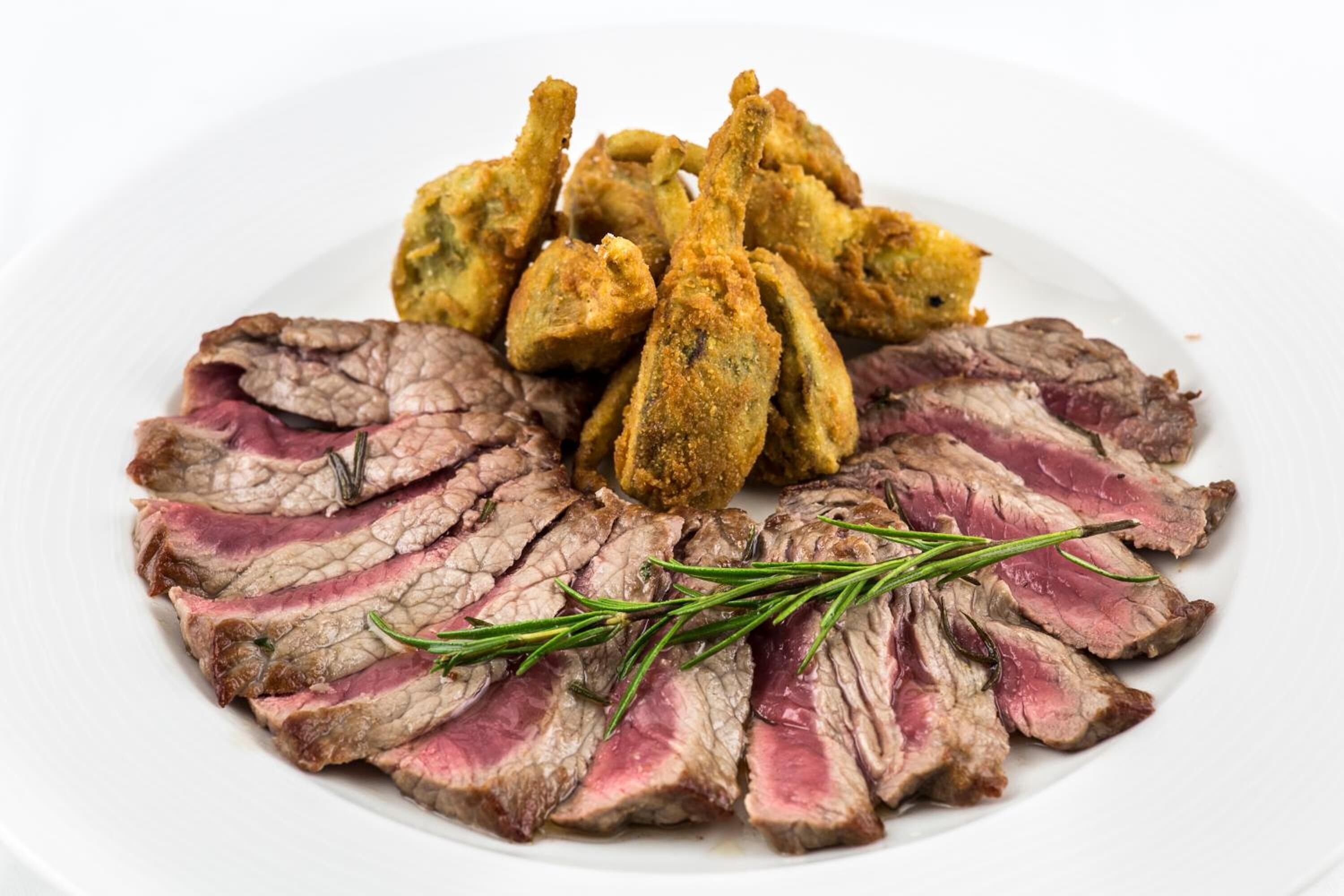 A plate with sliced steak and fried fish.