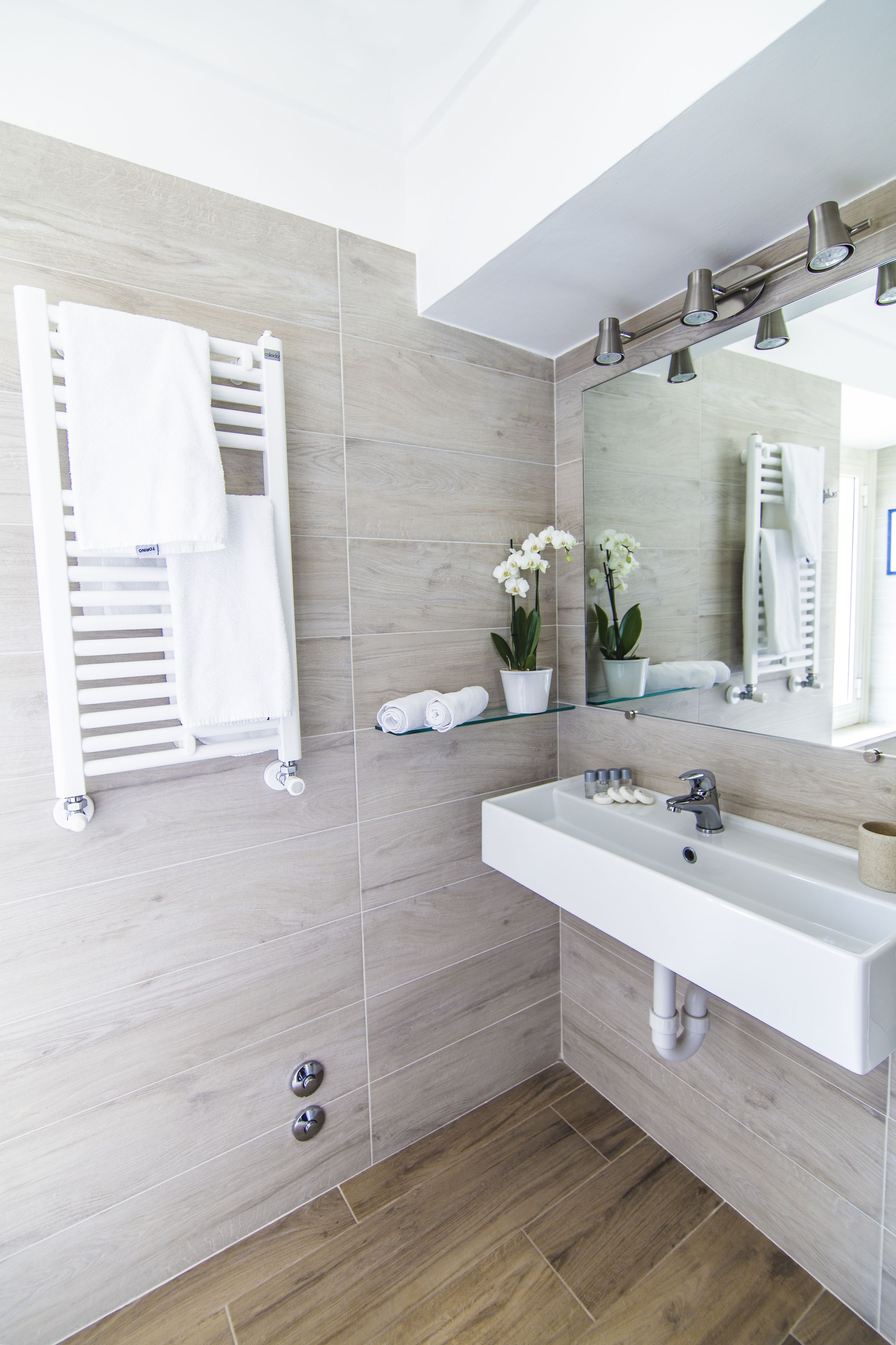 A modern bathroom with a white sink, mirror, and towel rack.
