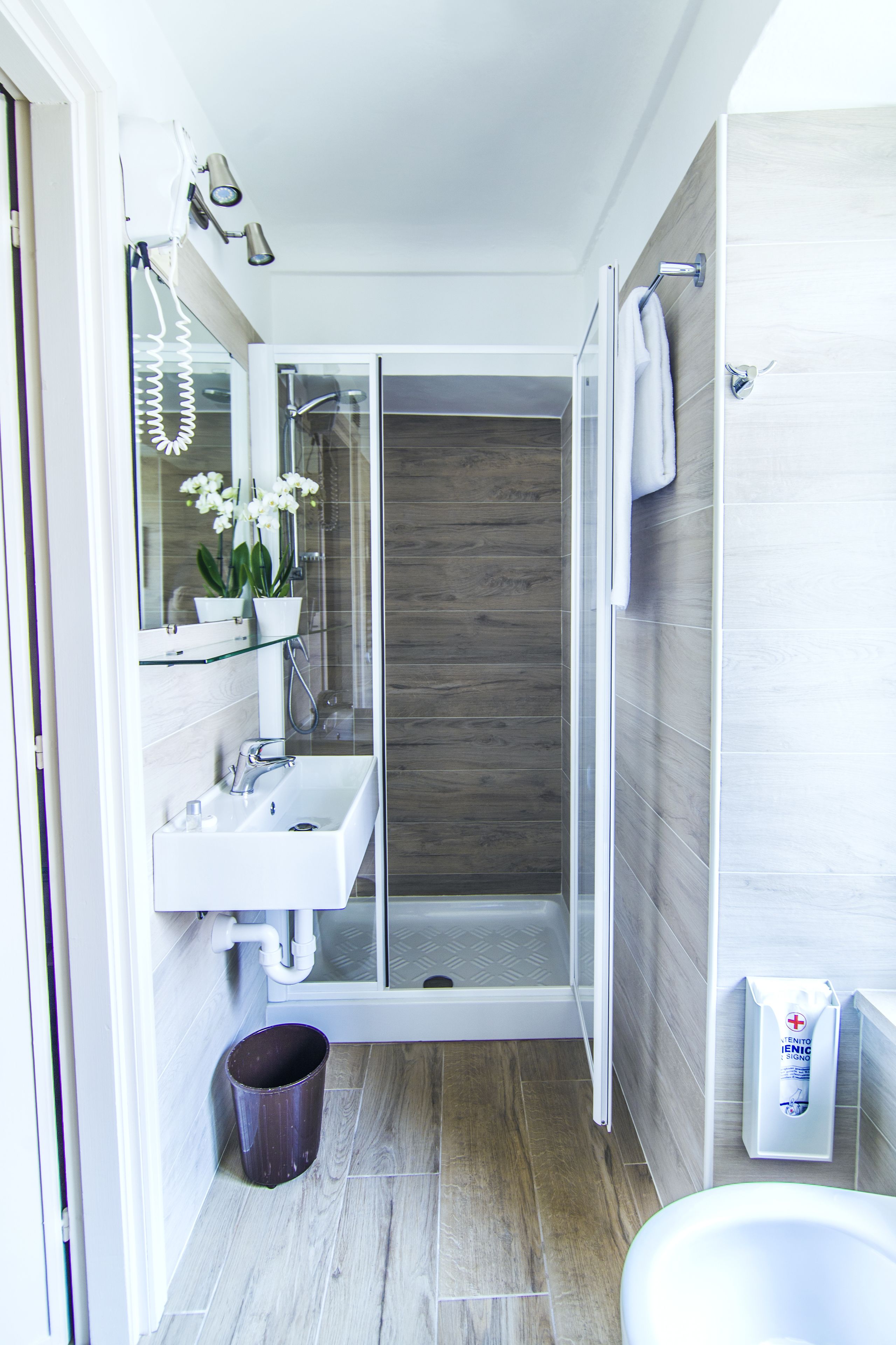 Une salle de bain moderne avec une douche à parois de verre, un lavabo blanc et un miroir au-dessus.