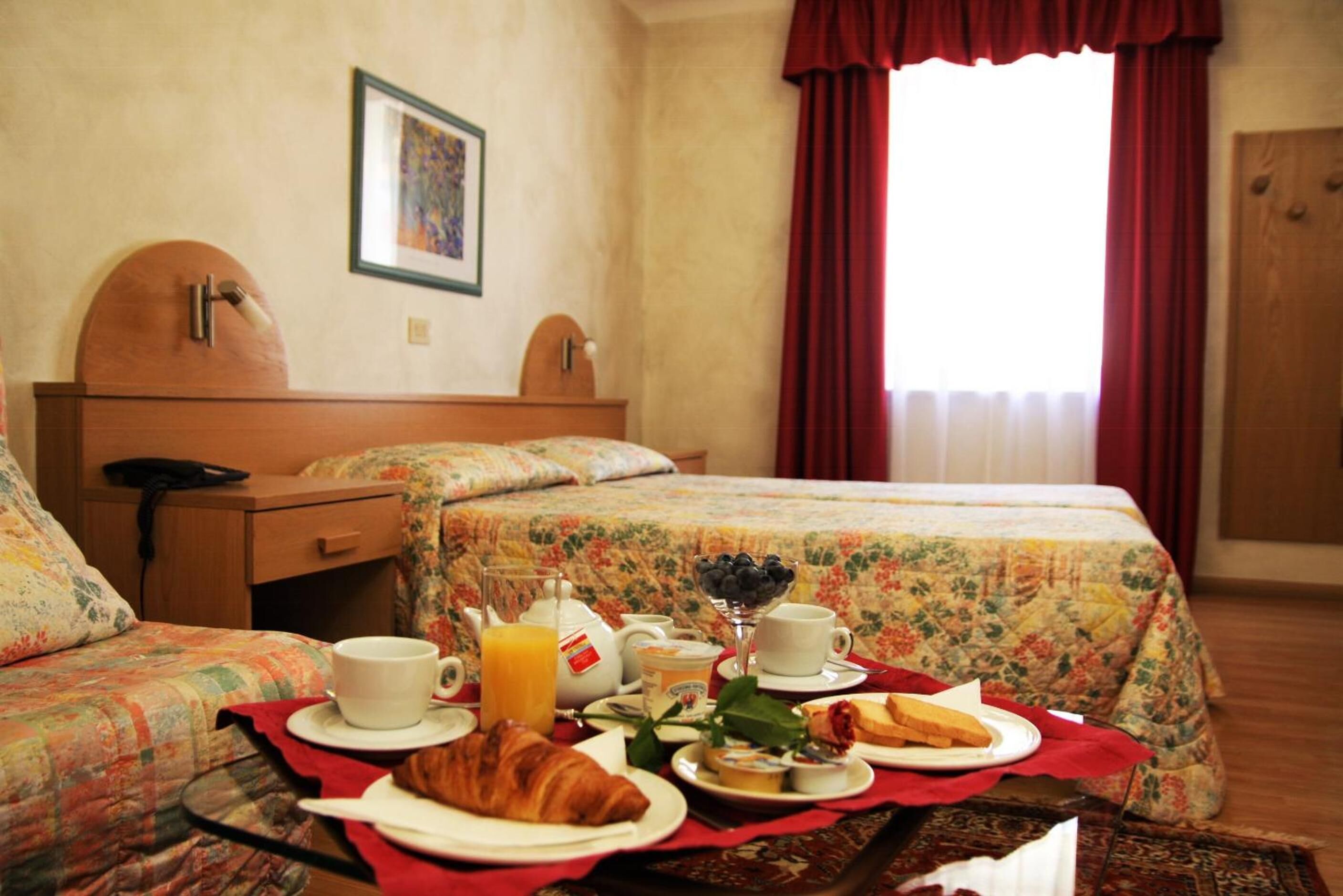 Ein Hotelzimmer mit Bett, Nachttisch, Stuhl und einem Frühstückstisch.