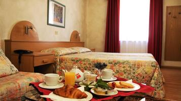 Ein Hotelzimmer mit Bett, Nachttisch, Stuhl und einem Frühstückstisch.